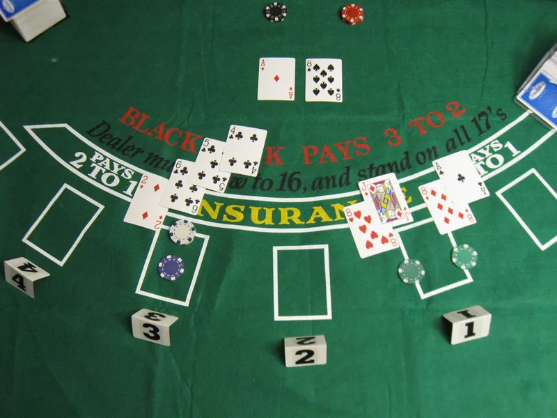 Blackjack table with cards, chips on a green board.