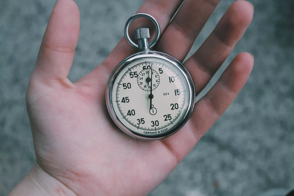 A round old style pocket watch in a hand.